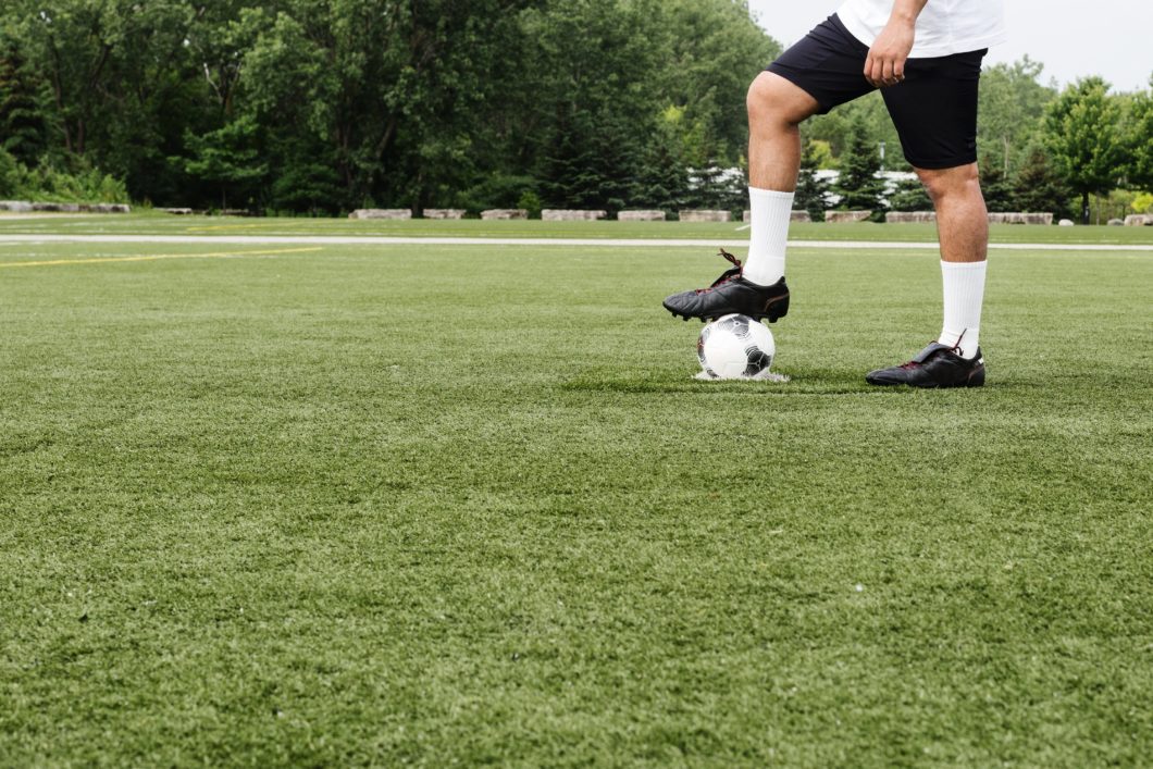 man holding soccer ball under his foot