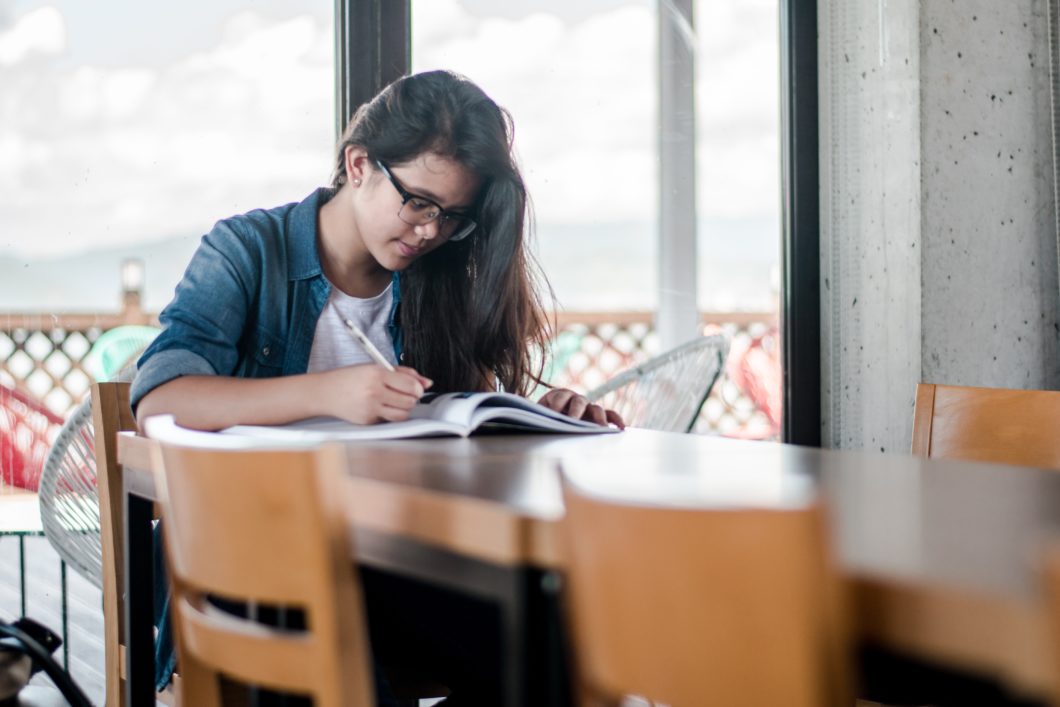 Girl looking down at textbook on table