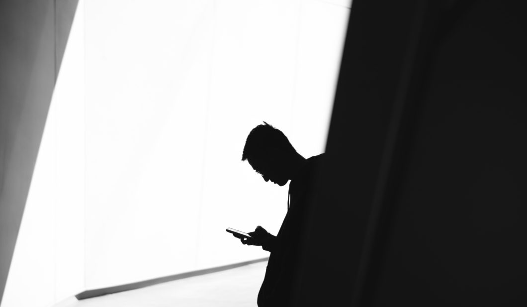 man's head tilted down looking at cell phone