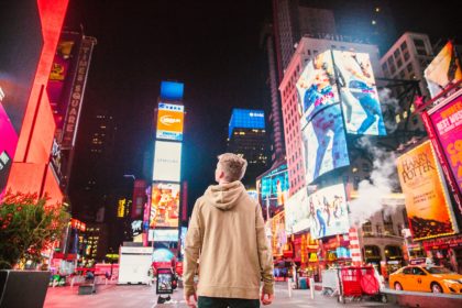 Young boy looking at bright screens at night in the city