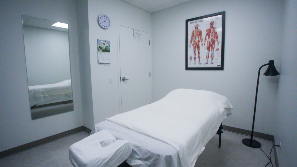 Massage room two at our Wynford location featuring a bed, mirror and artwork on the walls