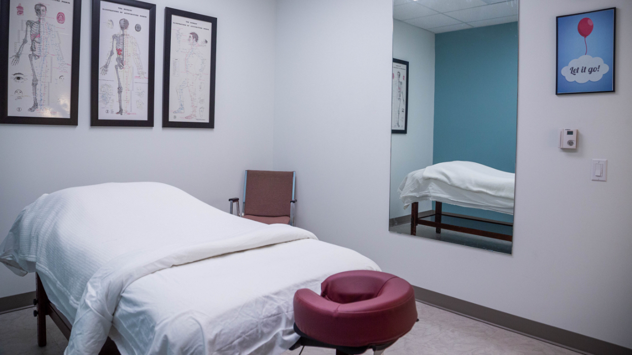 Massage room One at our Wynford location featuring a bed, mirror and artwork on the walls