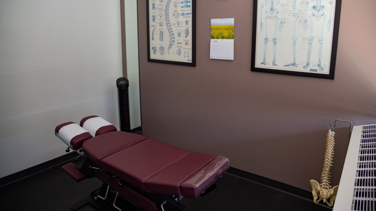chiropractic bed and model of a spine with images on the wall