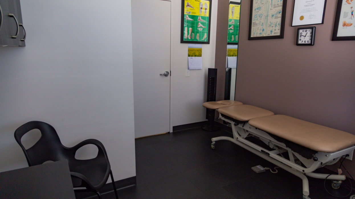 Physiotherapy room featuring a physiotherapy bed, with degrees and artwork on the walls