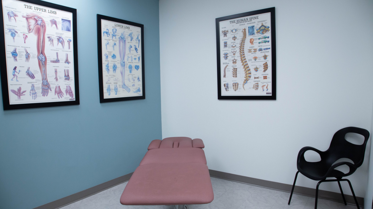 Osteopathy room with bed, chair, and artwork on the walls at our Wynford Location