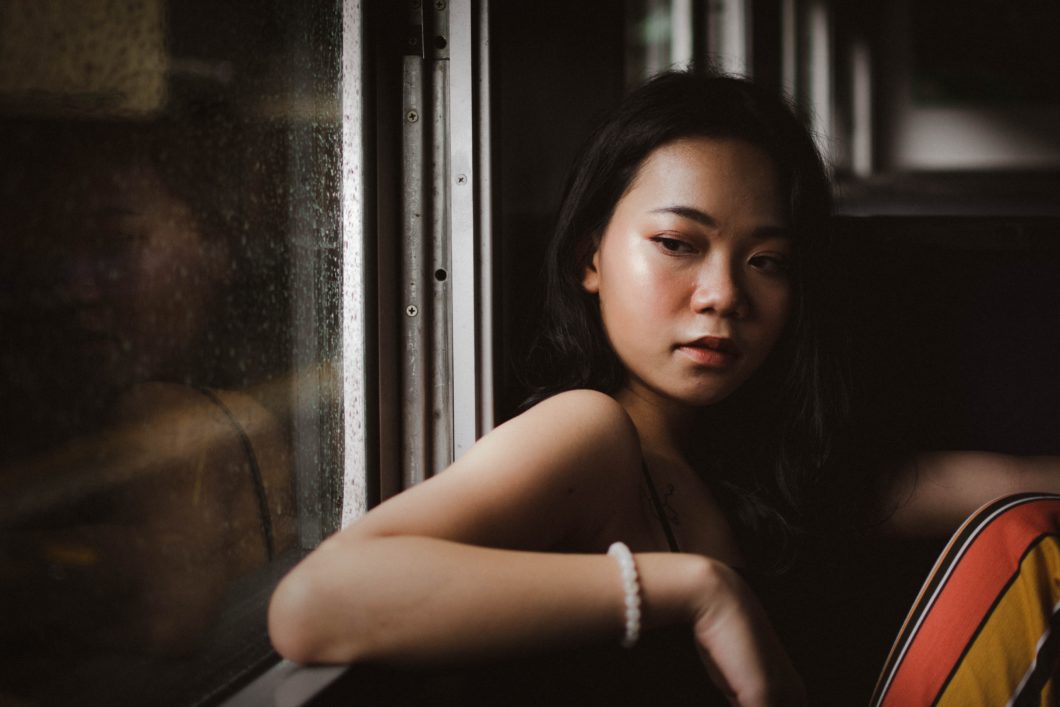 Woman at home alone looking out the window combating the covid-19 lockdown isolation