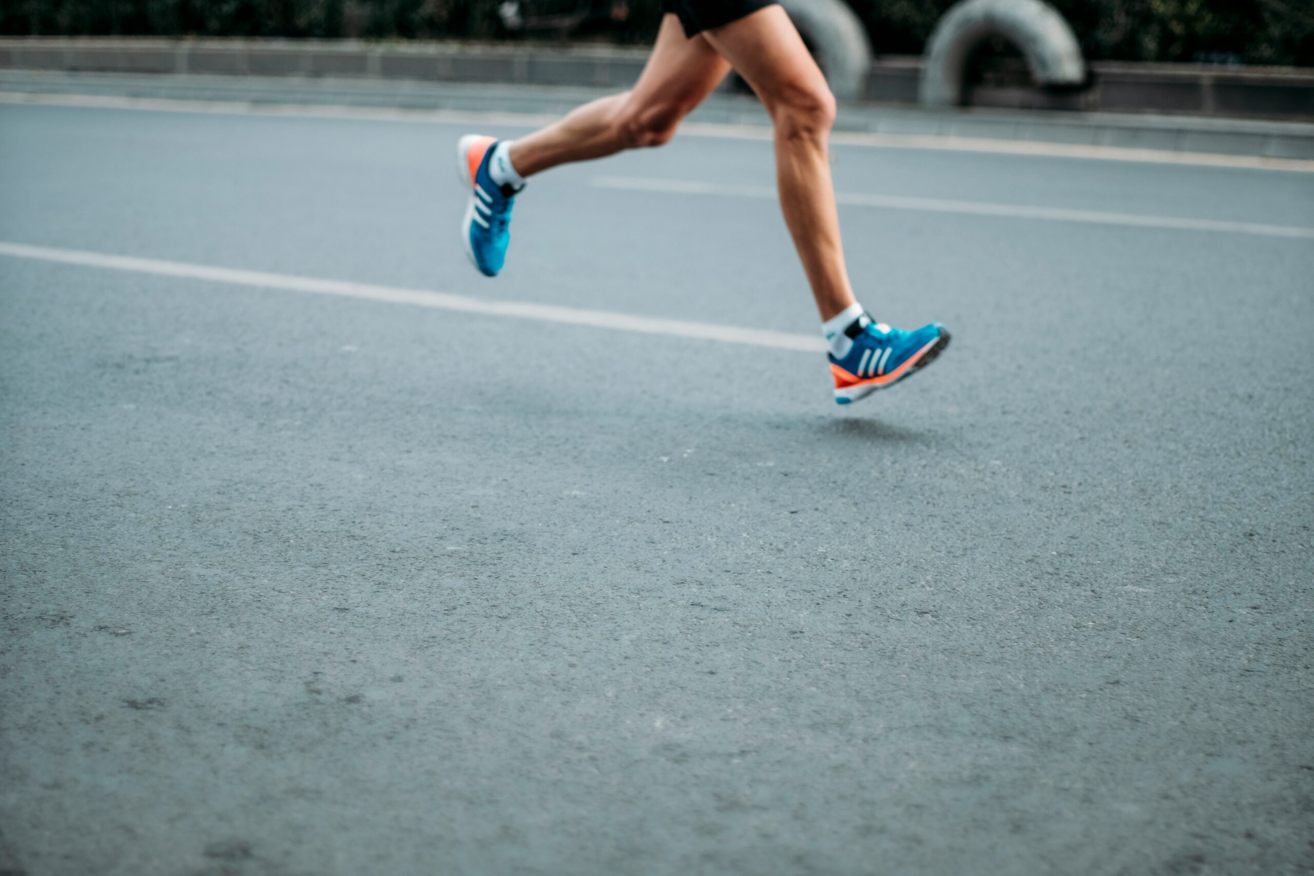 Physiotherapy patient running on pavement, close up of their legs